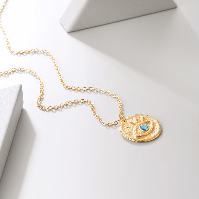 Close-up detail of Fettero® blue turquoise eye pendant necklace, polished gold with turquoise inlay craftsmanship for women