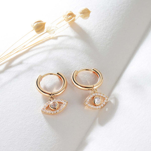 Close-up detail of Fettero® evil eye dangle earrings, polished gold finish with symbolic eye charm design