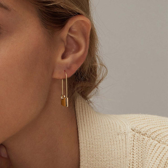 Model wearing Fettero® lock dangle gold earrings for women, elegant everyday wear jewelry with a modern statement style