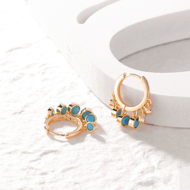 Close-up detail of Fettero® turquoise dangle huggie earrings, polished gold finish and sparkling turquoise for women