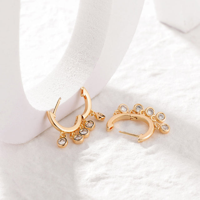 Model wearing Fettero® white CZ gold dangle huggie earrings for women, delicate everyday wear jewelry with sparkling cubic zirconia