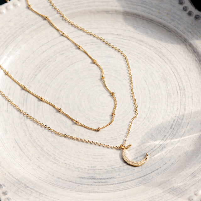 Close-up detail of Fettero® crescent moon necklace, polished gold finish and celestial pendant design for women