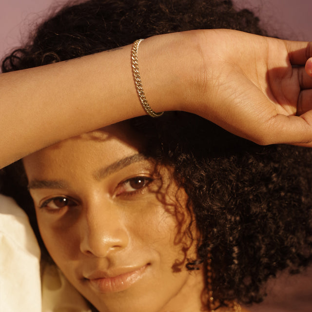 Model wearing Fettero® gold Cuban link chain bracelet for women, statement bracelet designed for everyday wear