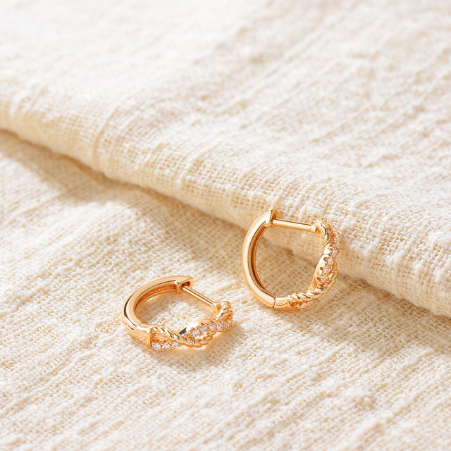 Close-up detail of Fettero® CZ twisted huggie earrings, polished gold finish and sparkling cubic zirconia for women