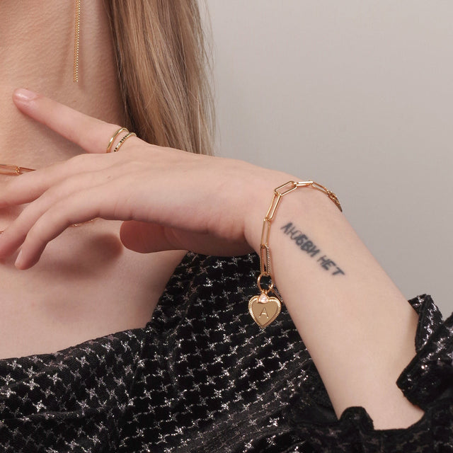 Model wearing Fettero® gold initial heart bracelet for women, delicate personalized bracelet for everyday wear