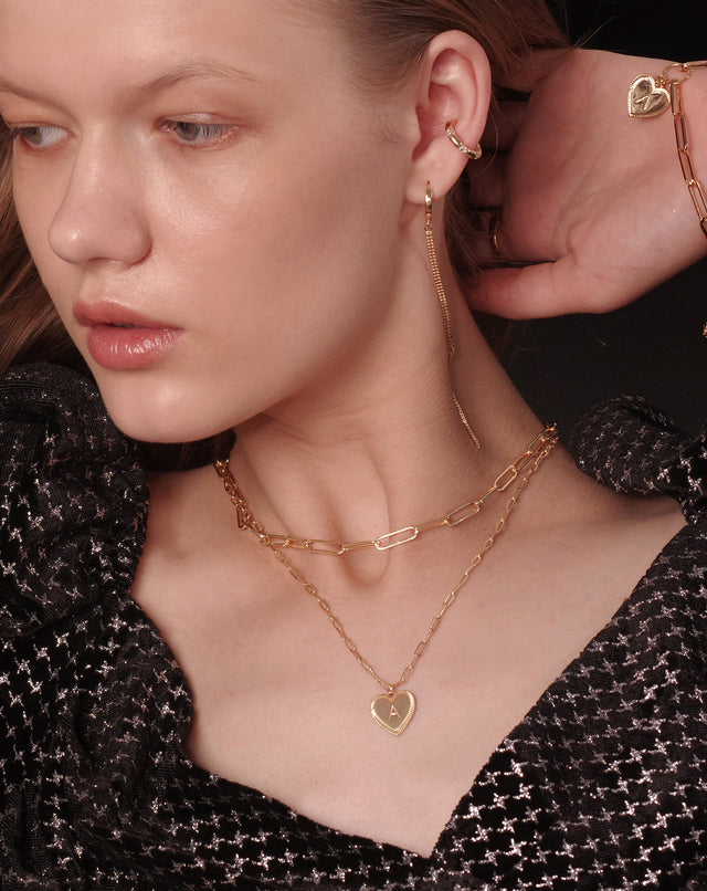 Model wearing Fettero® initial layered gold necklace for women, delicate everyday wear jewelry with stylish personalized charm