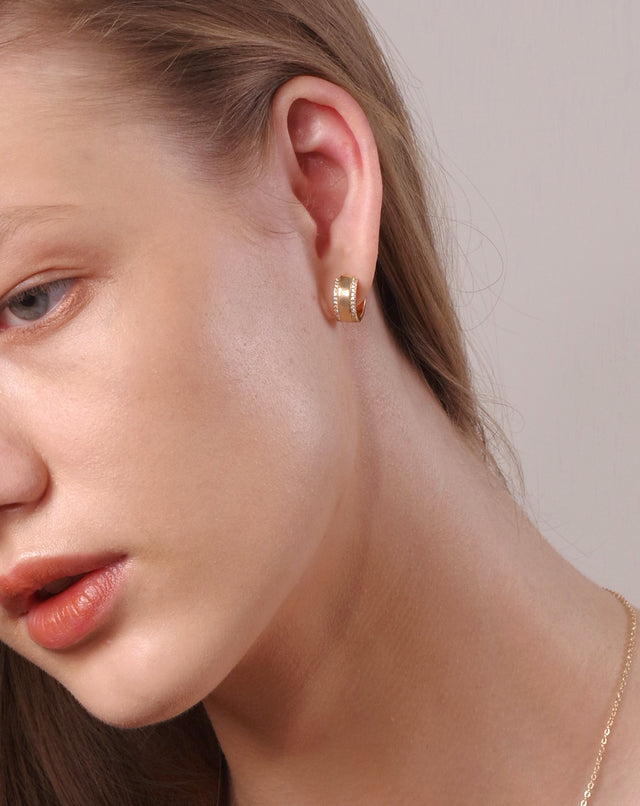 Model wearing Fettero® wide CZ gold huggie earrings for women, chic everyday wear jewelry with a modern look